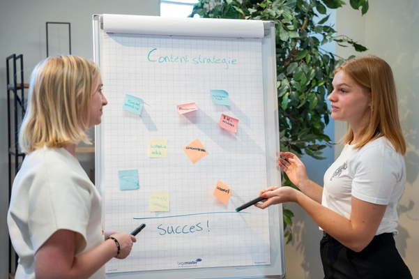 2 vrouwen bij flip-over bord met een contentstrategie en post-its erop