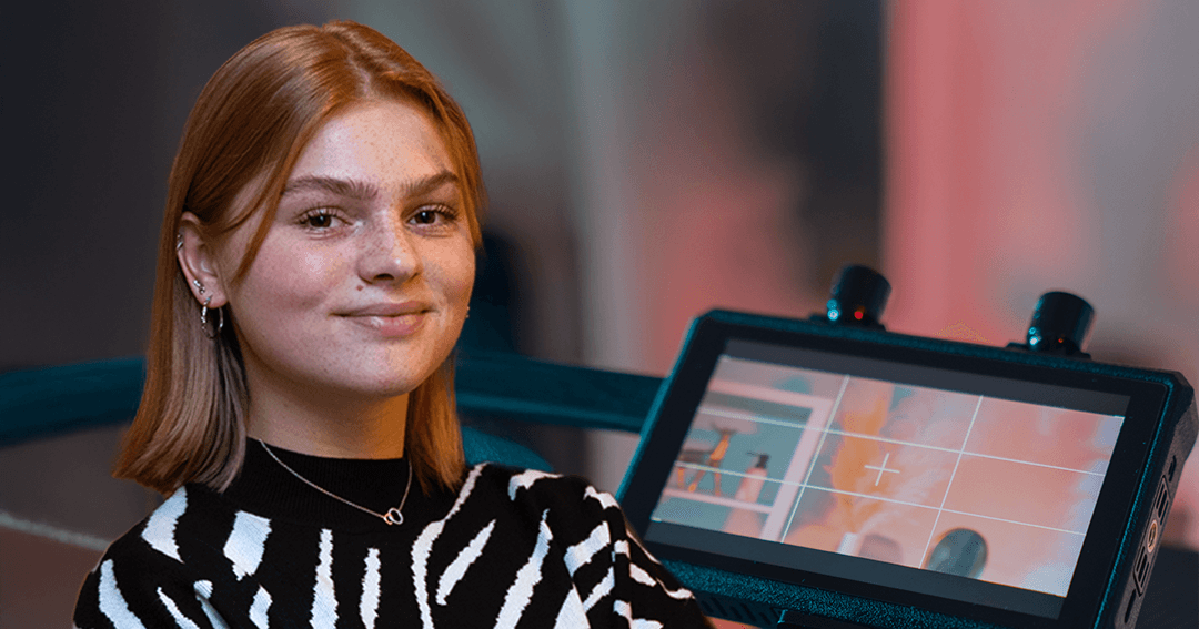 Lieke in zwart-wit gestreepte trui staat voor een camera met monitor.