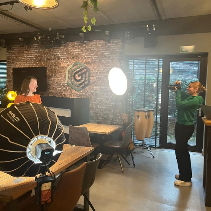 Fotoshoot met professionele verlichting en een fotograaf die een vrouw portretteert.