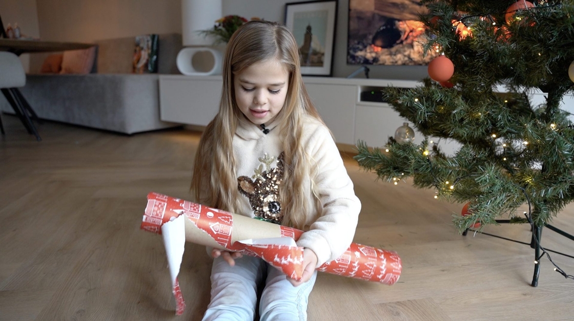 Meisje met cadeautje voor de kerstboom