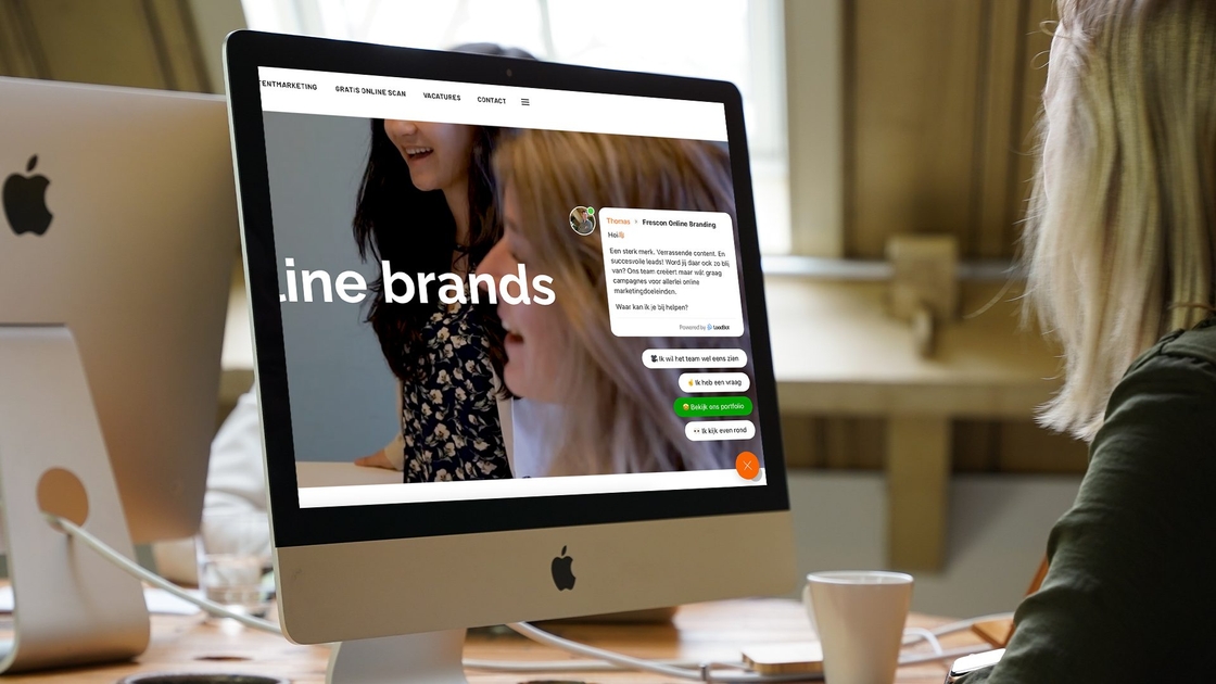 Vrouw kijkt naar Frescon-website met chatvenster op iMac.
