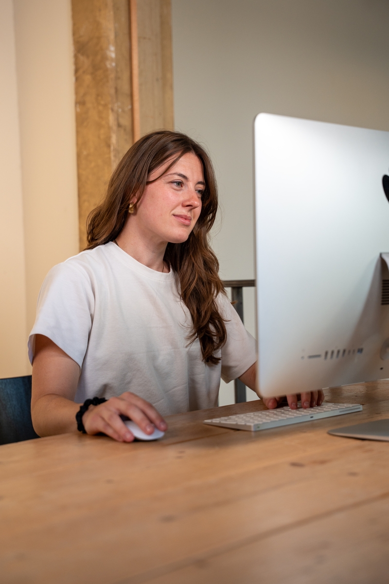 Dit is Amy, zij zit achter een bureau en werkt geconcentreerd achter een computer.
