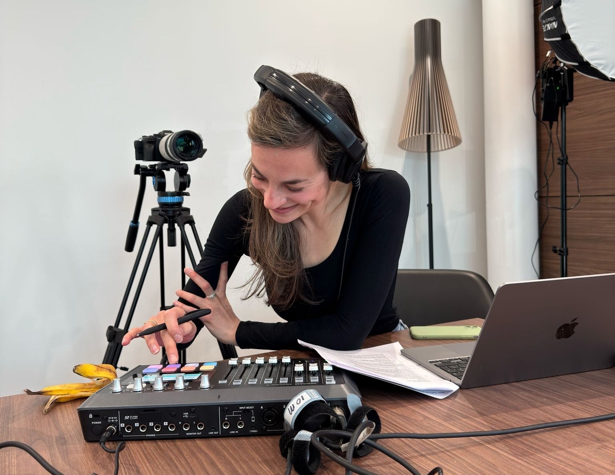 Vrouw bedient audiomixer met koptelefoon op in studio-omgeving.