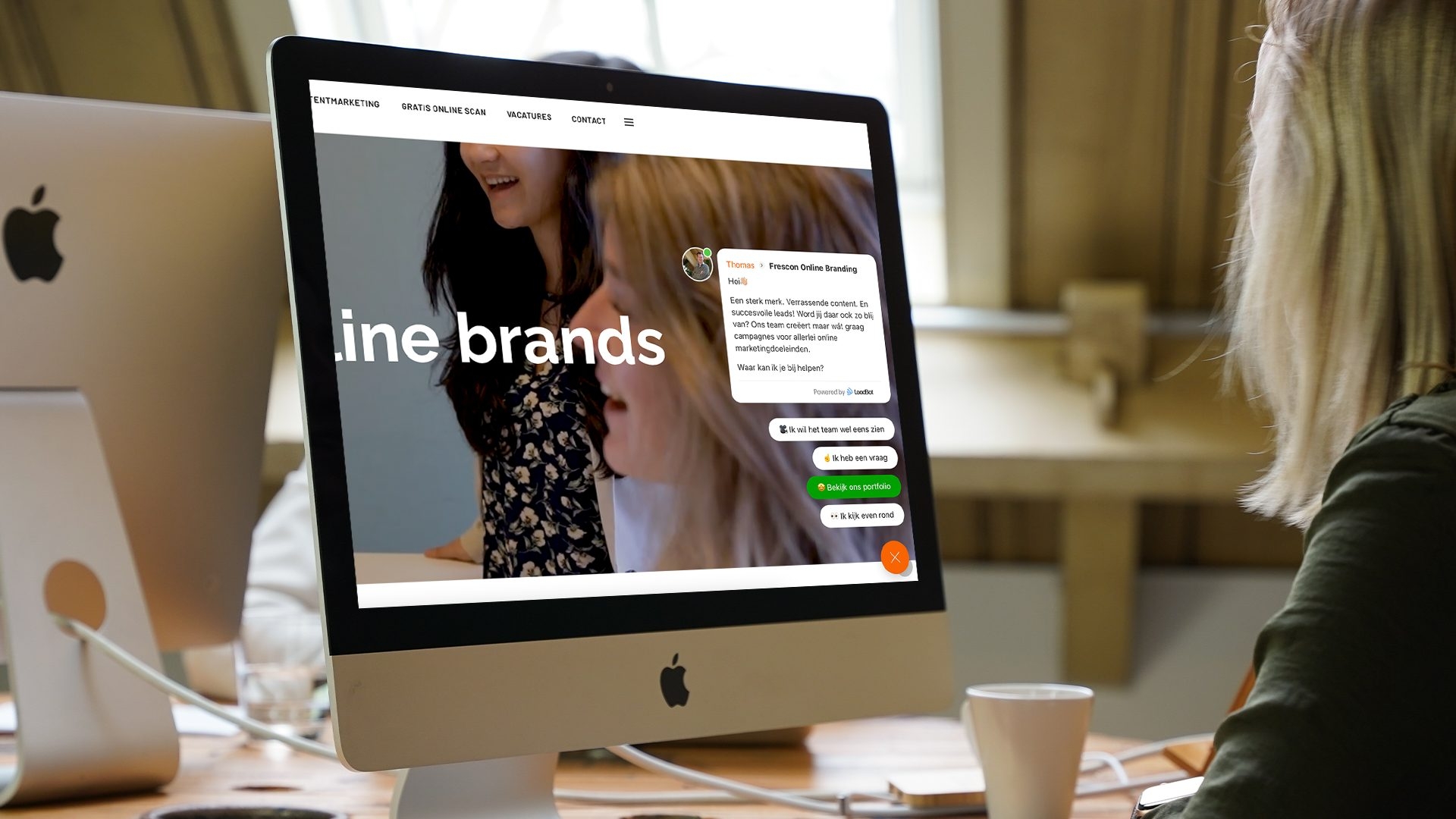 Vrouw kijkt naar Frescon-website met chatvenster op iMac.