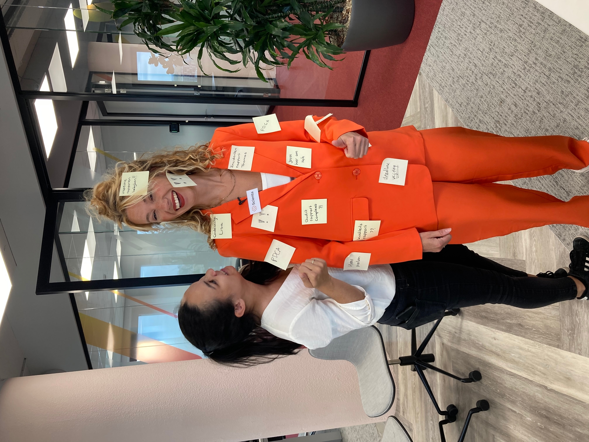 Kaylee en een vrouw van Woodwing die onder de post-it notes zit