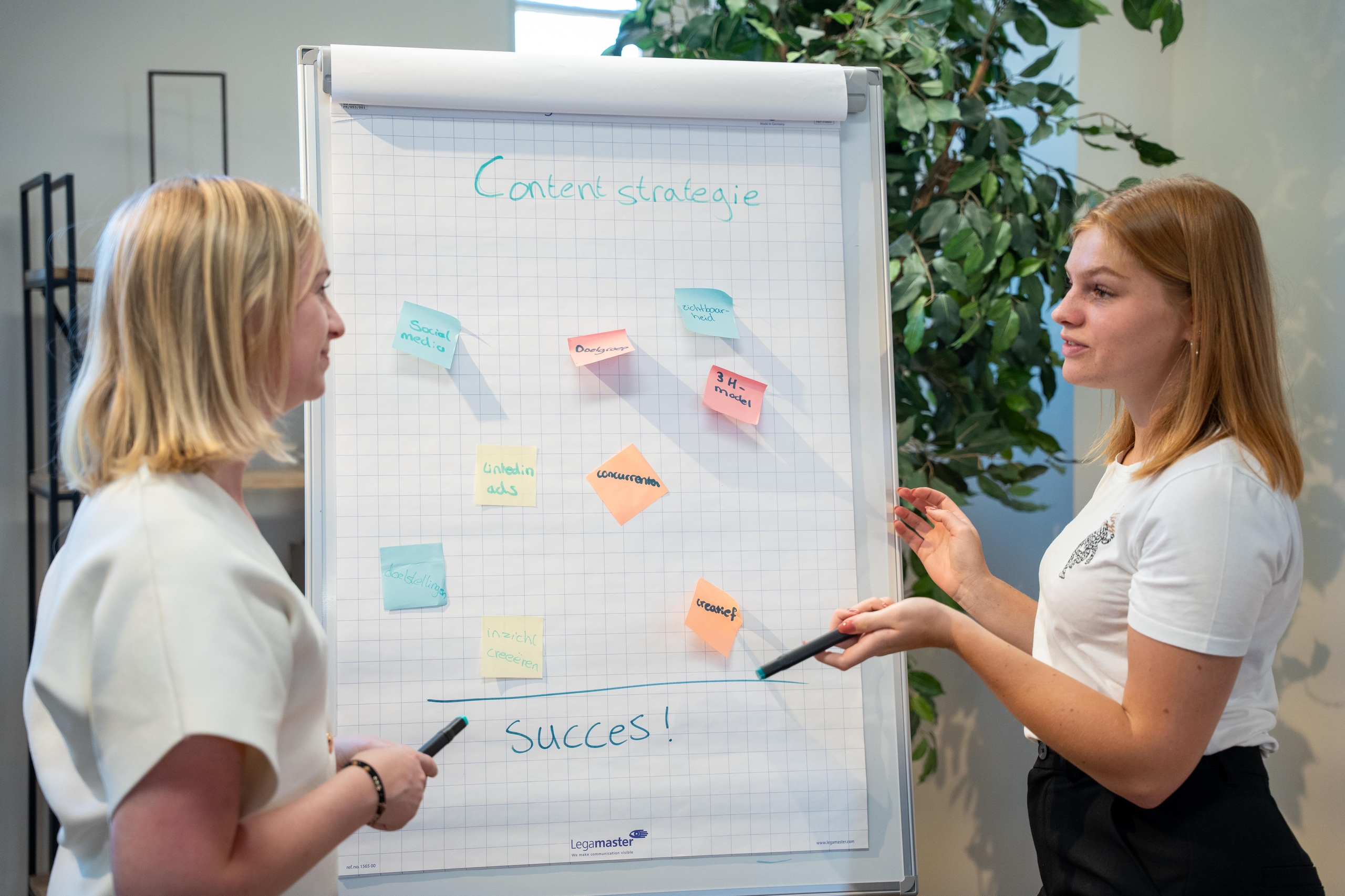 2 vrouwen bij flip-over bord met een contentstrategie en post-its erop