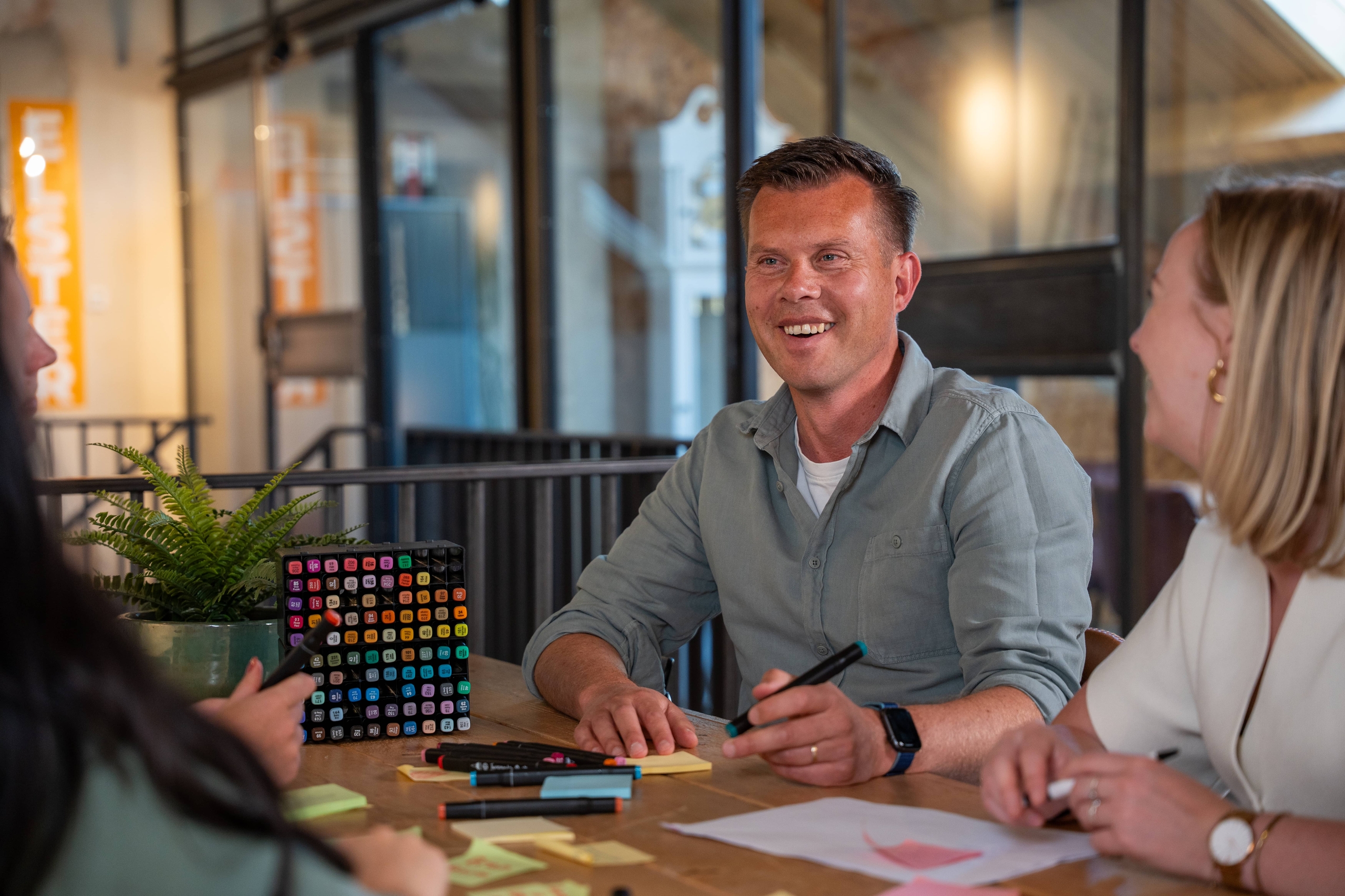 Lachende collega’s overleggen met stiften en post-its aan tafel. Online marketing bureau Deventer, Frescon team