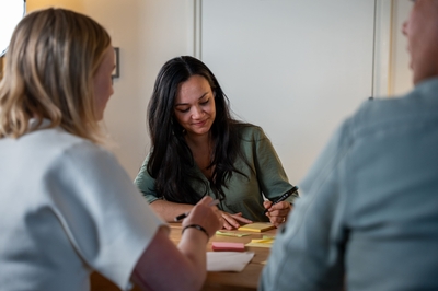Vrouw met pen glimlacht tijdens creatieve sessie met post-its.