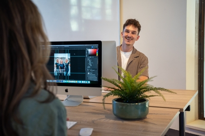 Collega’s werken samen aan een ontwerp op een iMac.