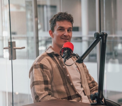 Jordi zit voor een podcastmicrofoon in de PCT studio.