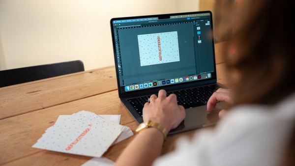 Amy achter computer met drukwerk kaartjes