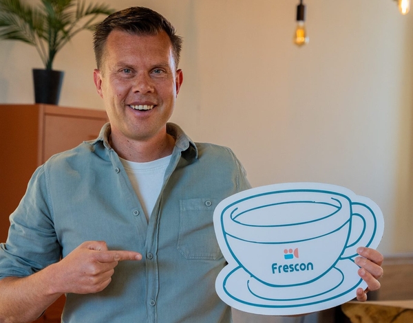 Man houdt koffiekop-icoon vast met Frescon-logo.