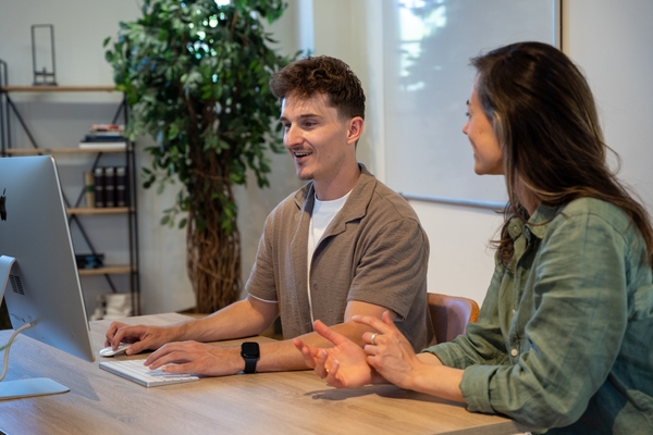 Twee collega’s werken samen achter een iMac.